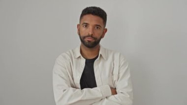 Genç, Afro-Amerikalı bir adam, gömlek giyiyor, kollarını kavuşturmuş, beyaz arka planda duruyor, olumsuz bir ifade takınıyor, şüpheci, sinirli ve onaylamıyor.