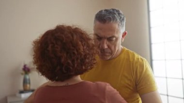 Oturma odasında kucaklaşan orta yaşlı çift duygusal bir anda sevgi ve destek gösteriyorlar.