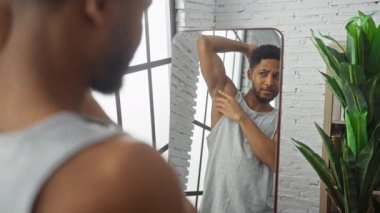 Yakışıklı, Afro-Amerikan bir adam, günlük giysiler içinde, aynada kendine bakıyor..