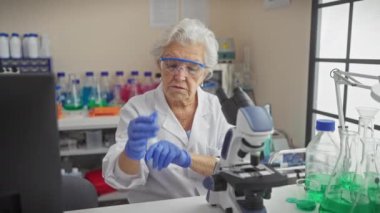Laboratuvar ortamında deney tüpünü inceleyen kıdemli kadın bilim adamı..
