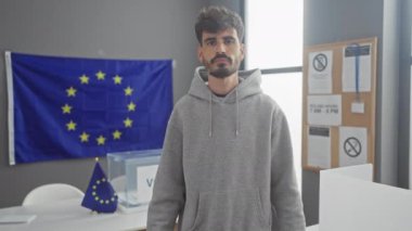Yakışıklı, İspanyol asıllı, elinde Avrupa Birliği bayrağıyla protesto tabelası tutan adam.