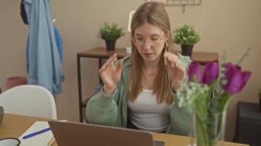 Odaklanmış bir kadın evde meditasyon yapıyor, ev bitkileriyle çevrili, sükuneti kucaklıyor..