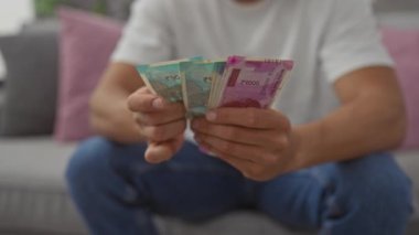 Genç İspanyol adam, rahat bir oturma odasında Hint rupileri sayıyor.