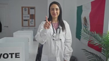 Steteskoplu neşeli genç bir kadın, oy kullanma merkezinde Meksika bayrağını sallıyor.