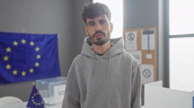 Genç bir İspanyol adam Avrupa Birliği bayraklarıyla konuşurken el kol hareketi yapıyor.