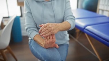 Olgun bir kadın bir fizyoterapi merkezinde el egzersizi yapıyor. Rehabilitasyon ve sağlık hizmetlerini kapalı bir ortamda gösteriyor..