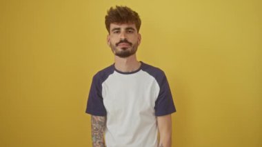 Genç İspanyol adam, mutlu bir şekilde ayakta duruyor, gözleri kapalı, izole edilmiş sarı bir arka planda 