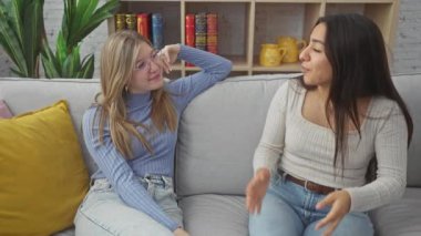 İki kadın, keyifli bir anı beşlikle kutlar ve sıcak bir oturma odasında kanepede kucaklaşır..