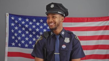 Kendinden emin bir Afro-Amerikan erkek polis memuru Amerikan bayrağı, rozeti ve radyosu önünde duruyor görünür, somut hizmet ve vatanseverlik..