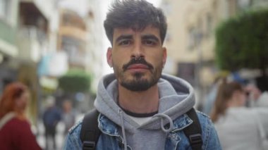 Şehir sokaklarında yürürken farklı duygular ifade eden yakışıklı sakallı bir adam..