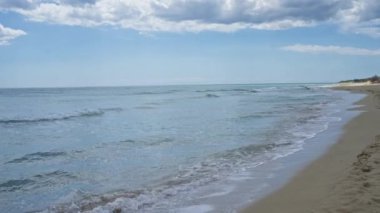 Pescoluse, Salento, Puglia, İtalya 'da sakin bir sahil. Parçalı bulutlu bir gökyüzü altında hafif dalgalar..