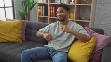 Keyifli bir adam rahat bir oturma odasında koltukta rahatlıyor ve kutlama yapıyor.