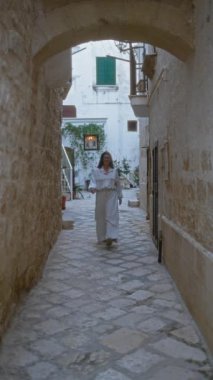 Genç bir İspanyol kadın polignano 'nun büyüleyici taş sokaklarında geziniyor Puglia, İtalya' da bir kısrak güzelliğini ve Avrupa manzarasını gözler önüne seriyor.