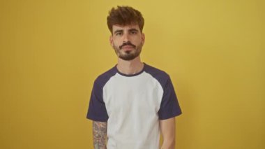 Bir dedikodu duymak için eğilen genç İspanyol adam, elini kulağının üzerinde, dikkatle dinleme; izole sarı bir arka plan karşı duran, duyma ve sağırlık kavramını somutlaştıran