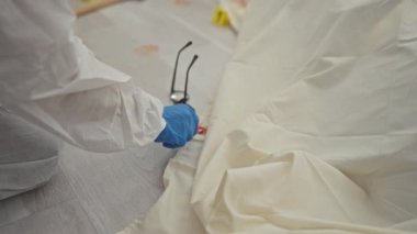 Koruyucu giysi üzerine adli tıp uzmanı olay yerinde kan lekeleriyle kanıt topluyor..