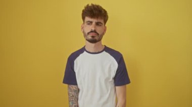 İzole edilmiş sarı arka planda duran genç İspanyol adam, el üstünde, unutulmuş hafıza veya hatanın farkına varıyor.