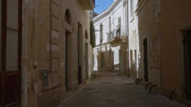 Bu Avrupa kasabasında tarihi mimari, sıcak güneş ışığı ve anımsatıcı Akdeniz cazibesine sahip Lecce, Puglia, İtalya 'da dar, boş bir taş ara sokak..