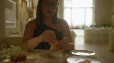 Genç İspanyol bir kadın zarif bir İtalyan restoranında yemek yiyor. Kapalı alanda, zeytinyağına batırdığı ekmeğe odaklanıyor..
