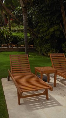 Tahta şezlonglar ve verandadaki yan masa huzurlu bir rahatlama ve lüks bir tatil yeri olduğunu gösteriyor..