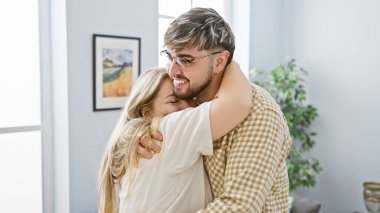 Sevgi dolu bir çift modern bir dairenin parlak, samimi oturma odasında sıcacık kucaklaşıyorlar..