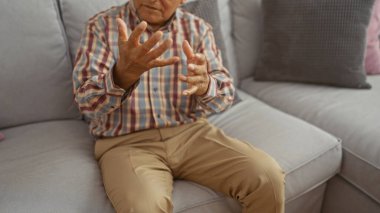 Yaşlı adam sohbete daldı, sıcak bir oturma odasında otururken el kol hareketi yaptı..