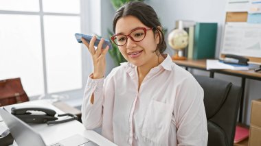 Genç bir İspanyol kadın ofisinde profesyonelliği ve modern iletişimi anlatan bir sesli mesaj dinliyor..