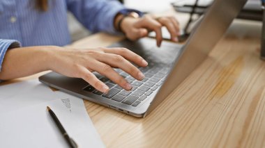 Modern ofis düzeninde dizüstü bilgisayarda yazı yazan İspanyol kadın. Ahşap masa ve belgelerle..