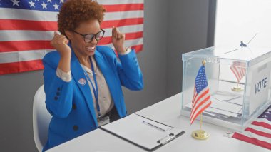 Heyecanlı mavi takım elbiseli Afro-Amerikalı kadın önümüzde bayrak ve oy sandığıyla kutlama etiketi yapıştırdı..