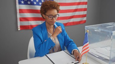 Mavi ceketli Afrikalı Amerikalı kadın içeride bizimle birlikte oy veriyor..