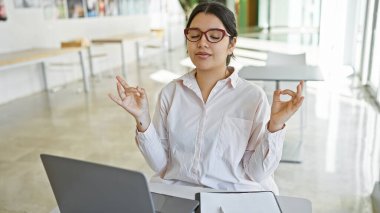 Genç bir İspanyol kadın işyerinde meditasyon yapıyor, refahı ve farkındalığı arttırıyor..