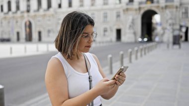 Genç ve güzel İspanyol kadın Viyana sokaklarında akıllı telefon kullanıyor.