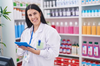 Eczanede çalışan dokunmatik ped kullanan genç, güzel İspanyol kadın eczacı.