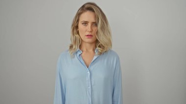 Mavi gömlekli, genç, güzel, sarışın bir kadının portresi beyaz bir arkaplan karşısında durup düşünceli bir ifade sergiliyor..