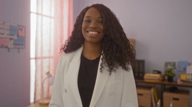 Kıvırcık saçlı, güzel, Afro-Amerikan kadın. Arka planda ofis malzemeleriyle bir dedektifin ofisinde güvenle duruyor..