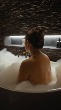 Huzurlu bir kadın lüks, taş duvarlı bir banyoda şen şakrak bir banyo yapar. Huzur ve özgüven uyandırır..