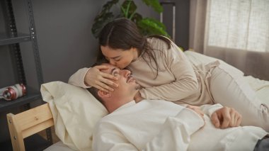Sevgi dolu bir kadın yatakta erkeğin yüzünü okşuyor, sıcak bir yatak odasında ilişki ve şefkat duygusu taşıyor..
