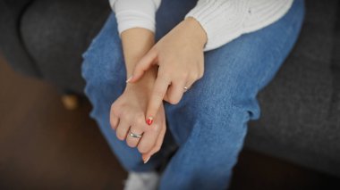 Genç bir kadın evinde parmağında gümüş bir yüzük gösteriyor, davetkar ve samimi bir ortam yaratıyor..