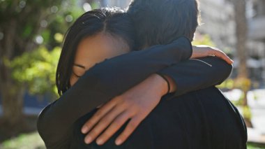 Irklar arası çift, güneşli bir parkta sevgi ve çeşitlilik içinde kucaklaşır.