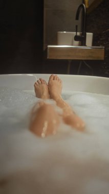 Bir kadın lüks bir otel banyosunda köpük banyosunda dinlenmekten zevk alır.