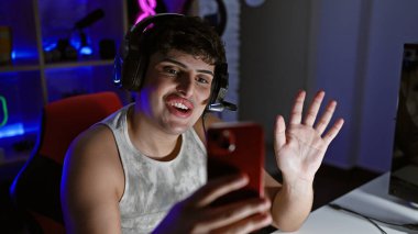 Neşeli genç bir adam, gece vakti neon ışıklı bir oyun odasında akıllı telefondan akarsu gibi akıyor..