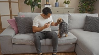 Genç Asyalı bir adam köpeğiyle bir apartman dairesinde oynuyordu..