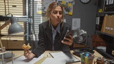 Genç bir kadın dedektif, yoğun bir karakolda telefonunu incelerken atıştırmalık yemekten hoşlanır..