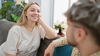 Gülümseyen bir kadın, sıcak bir dairede, sevgi dolu bir ilişkiyi ve aile hayatını yansıtan bir adamı dinler..