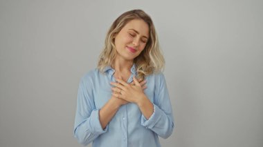 Mavi gömlekli genç sarışın bir kadın. Gözleri kapalı gülümsüyor. Beyaz bir arka plana bakıyor..