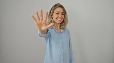 Young blonde woman in a blue shirt showing number five with her hand, isolated on white background clipart