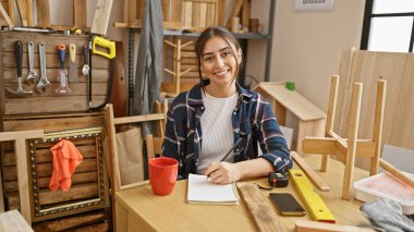 Ahşap atölyesinde aletler ve kereste projeleriyle gülümseyen İspanyol kadın.