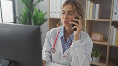 Laboratuvar önlüklü çekici sarışın kadın doktor klinikte telefonla konuşuyor..