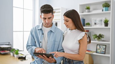Profesyonel bir erkek ve kadın takımı, modern ofis içinde bir tablet kullanıyorlar..