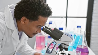 Modern bir laboratuvar ortamında örnekleri mikroskop altında analiz eden yakışıklı bir adam.