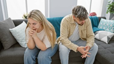 Endişeli bir çift modern bir oturma odasındaki koltukta oturmuş ilişkilerinde gerginlik gösteriyorlar..